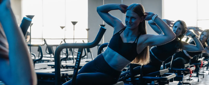 Women performing core-focused Lagree movements on Megaformer machines at TIGHT Dallas, maintaining slow, controlled form.