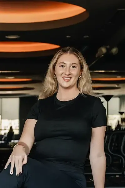 Fitness instructor Hallie Walters smiling in a studio wearing black athletic wear.