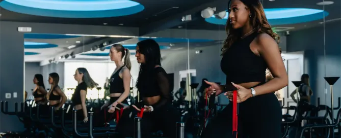 Women in black activewear working out on Megaformer machines during a Lagree class at TIGHT Dallas