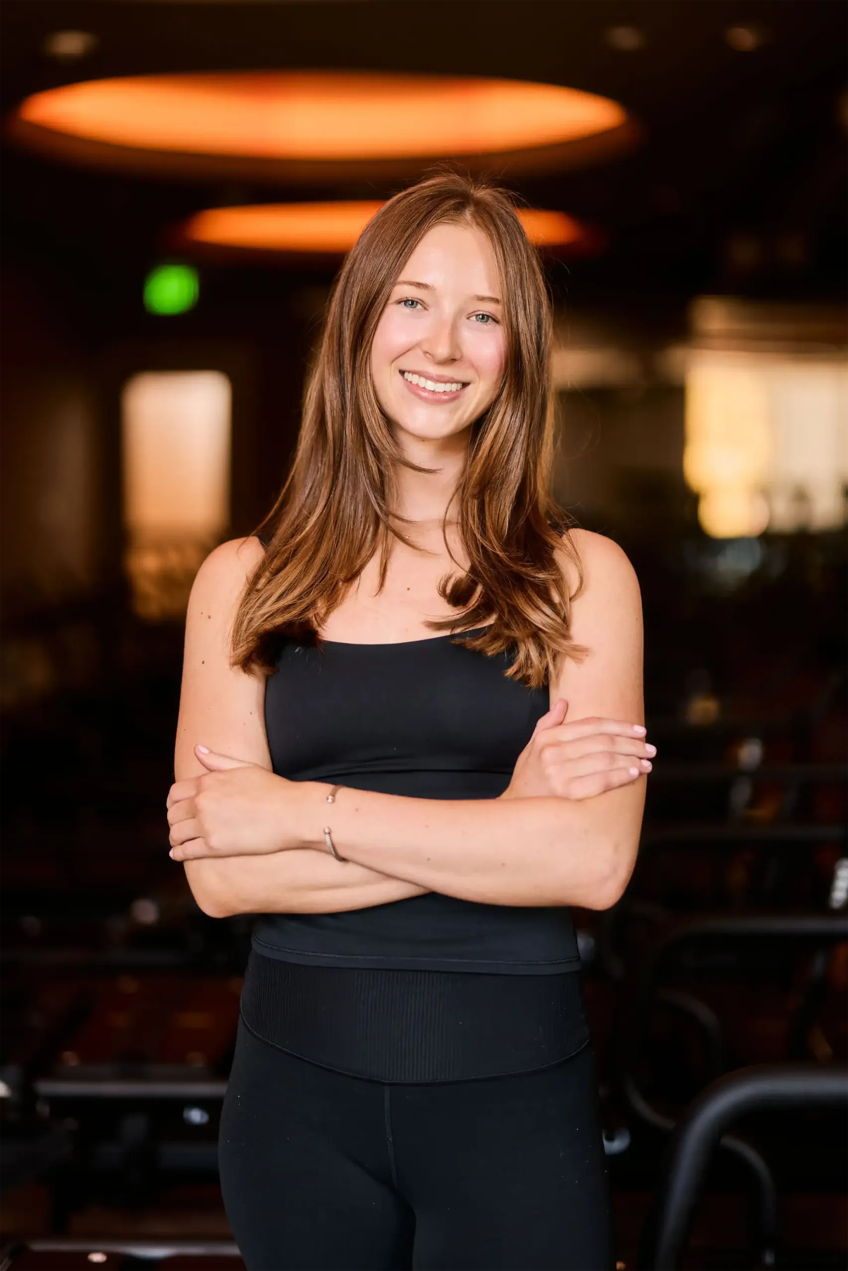 hannah-studio-manager-lagree-floor-tight-dallas. Hannah, studio manager at TIGHT Dallas, standing with arms crossed on the Lagree studio floor